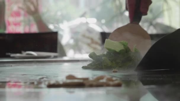 Disparo en cámara lenta de experto chef teppanyaki cocinar verduras
 - Metraje, vídeo