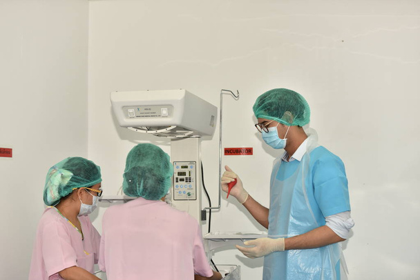 手術室で働いているチーム外科医。手術室での外科的光。カットで外科手術の開始の準備.外科医は患者の手術をしています. - 写真・画像