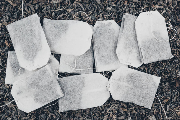 Paper tea bags on dry tea as background - Photo, Image