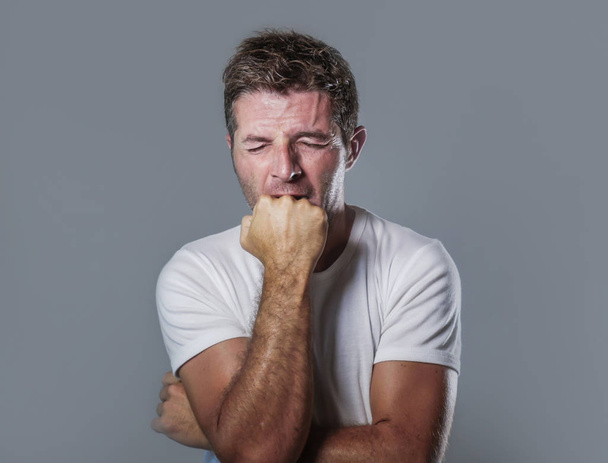 portrait of sad and depressed man biting his fist desperate feeling frustrated and helpless in depression and sadness facial expression concept isolated grey background - Fotoğraf, Görsel