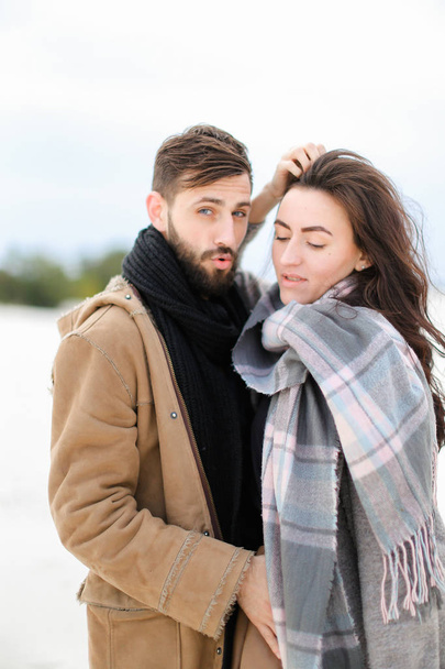 Joven mujer con bufanda gris de pie con el hombre de abrigo, fondo blanco de invierno
. - Foto, Imagen