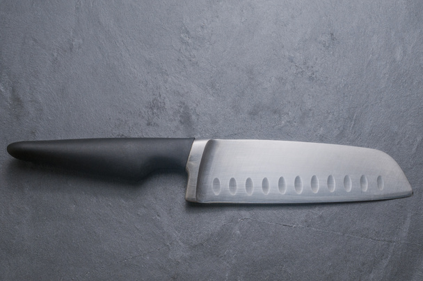 Кухарський ніж, що кладе сірий стіл з каменю
 - Фото, зображення