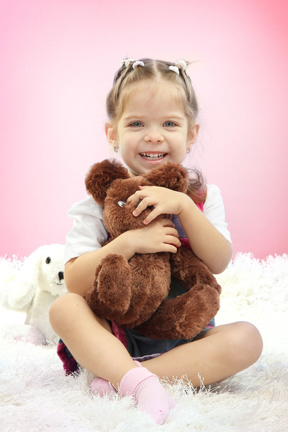 Aranyos kis lány játék-játék medve, rózsaszín háttér - Fotó, kép