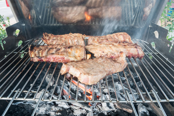 On charcoal barbecue there are ribs and a tasty steak - Foto, immagini