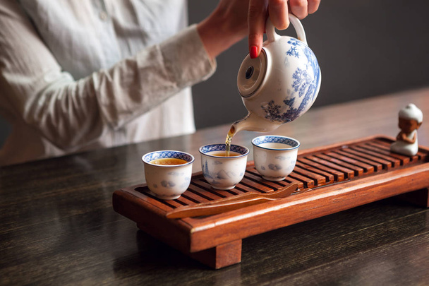 Cropped shot of woman pouring tea in traditional chinese teaware. - Foto, afbeelding