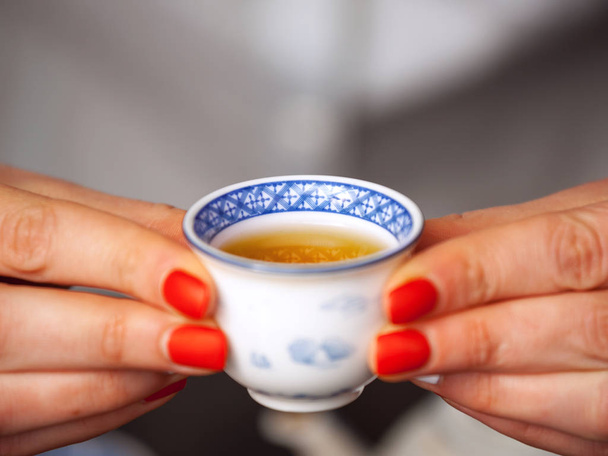 Cropped shot of woman holding traditional chinense teacup with oolong green tea. - Foto, afbeelding