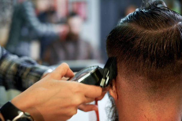 Master cuts hair and beard of men in the barbershop - Photo, Image