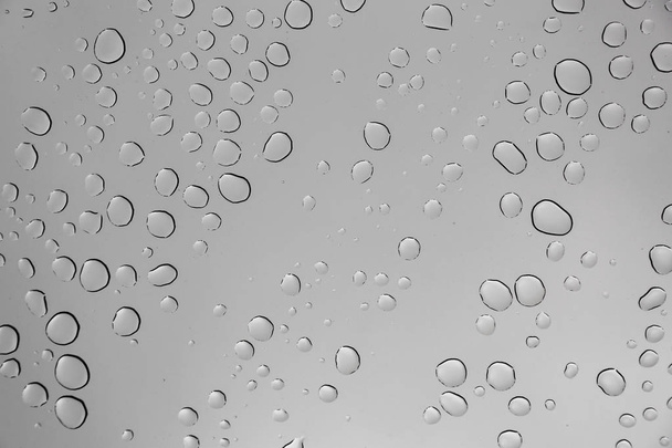 Σταγόνες βροχής σε γυάλινη επιφάνεια παραθύρου με θολό φόντο . - Φωτογραφία, εικόνα