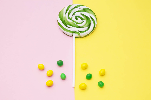 colorful lollipops and assortment of candies on yellow and pink background - Foto, Imagem