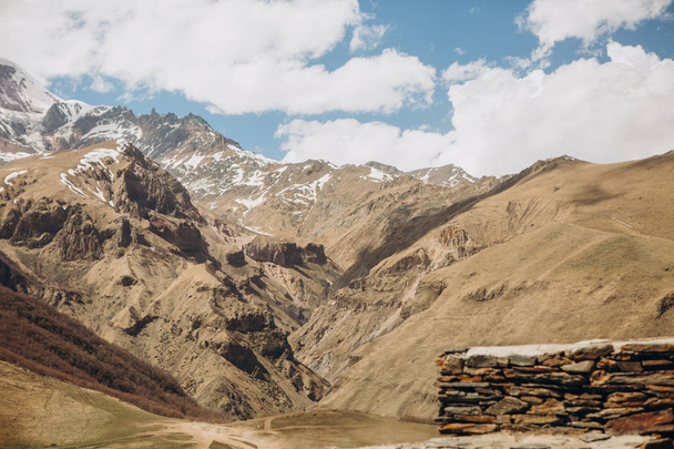 road to the Kazbek mountain with a stone fence and a view of the snowy mountain range - Foto, Imagen