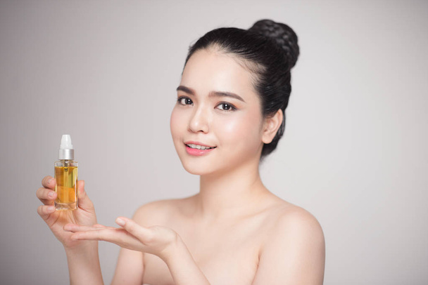 Concepto de belleza. Asiática bonita mujer con perfecta piel celebración botella de aceite
 - Foto, Imagen