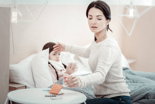 Serious female person treating her daughter - Foto, imagen