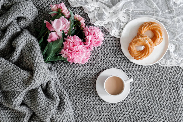 A cup of coffee with sweets and peonies on a gray background - Foto, imagen