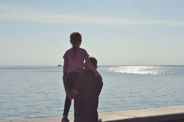 Dad and daughter are looking at the sea - Фото, изображение