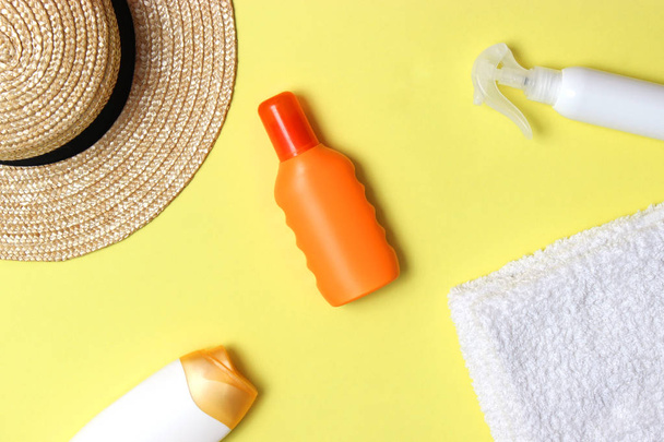 Sonnencreme, Handtuch, Hut, Brille auf farbigem Hintergrund. Kosmetik zur Vermeidung von Sonnenbrand. Draufsicht, Flatlay  - Foto, Bild