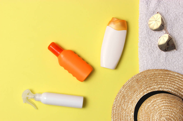 sunscreen, towel, hat, glasses on a colored background. Cosmetics for prevention of sunburn.top view, flatlay  - Foto, Imagem