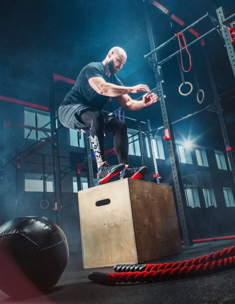 Man jumping during exercises in the fitness gym. CrossFit. - Foto, afbeelding
