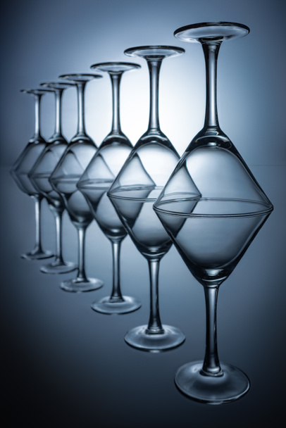ряд прозрачных бокалов мартини на сером с отражениями
 - Фото, изображение