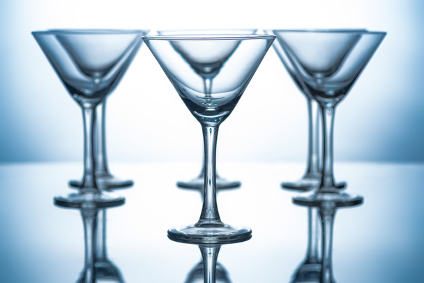 row of empty martini glasses on grey with reflections - Фото, зображення