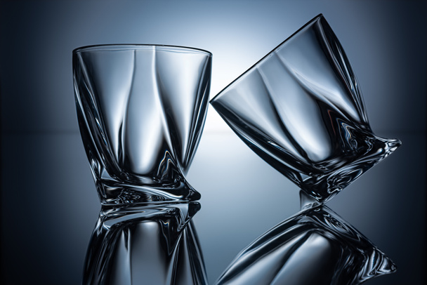 two transparent empty cognac glasses on grey with reflections - Foto, afbeelding
