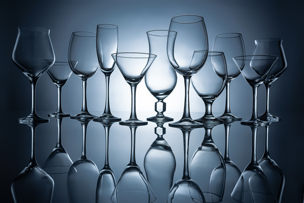 siluetas de diferentes vasos vacíos con reflejos, sobre gris
 - Foto, Imagen