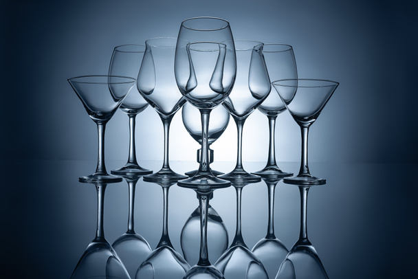 verschillende lege wijnglazen met reflecties, op grijs - Foto, afbeelding