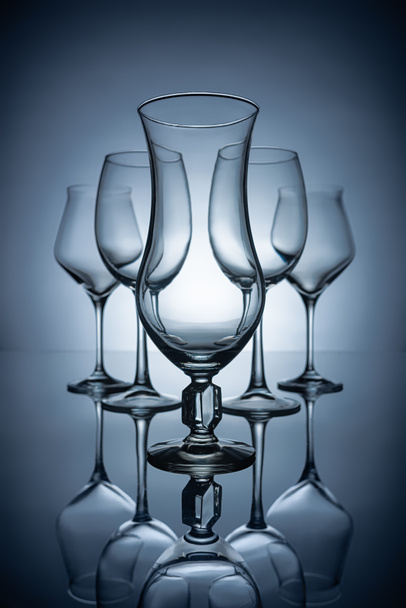 silhouettes of different empty wine glasses with reflections, on grey - Фото, зображення