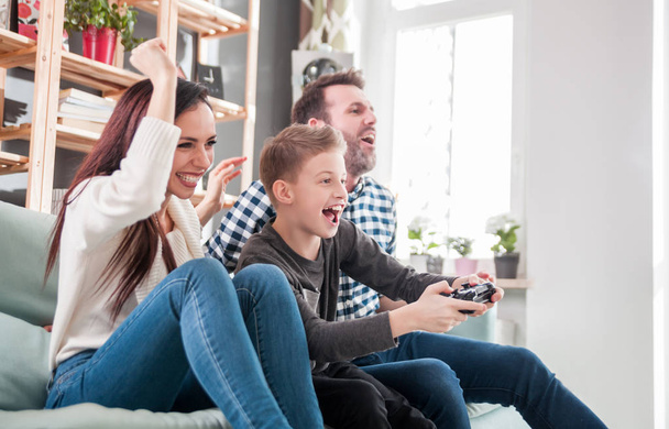 Excited family playing video game on console at home - Foto, Imagen