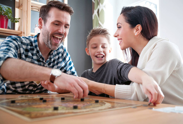 Happy family absorbedly playing board game at home - 写真・画像