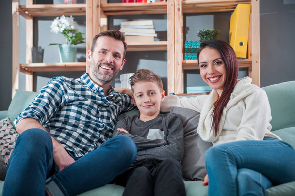 Young happy loving family sitting on sofa at home - Foto, afbeelding