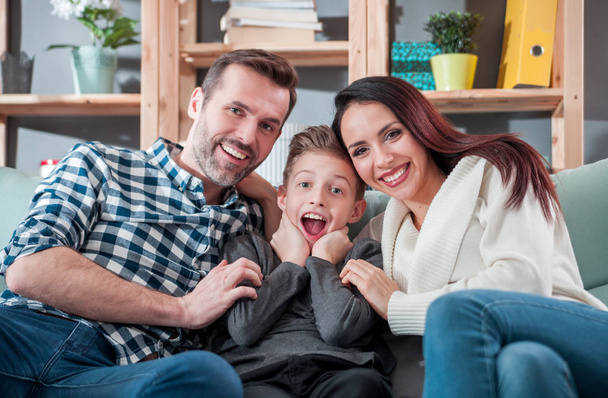 Young happy loving family sitting on sofa at home - Photo, Image