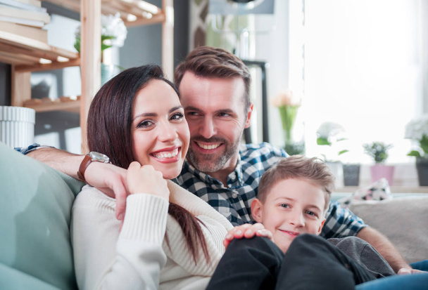Young happy loving family sitting on sofa at home - Photo, Image