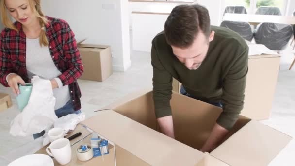 Młode małżeństwo pakowania rzeczy do pudełka - Materiał filmowy, wideo