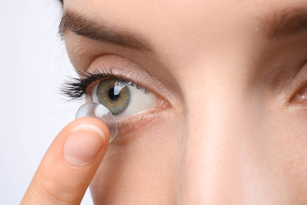 Jonge vrouw contactlens aanbrengend haar oog, close-up - Foto, afbeelding
