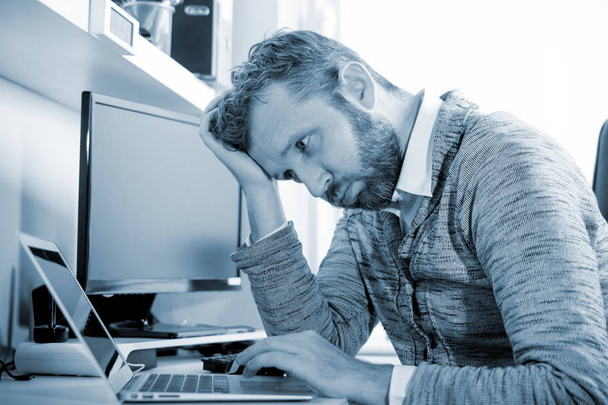 Перероблений втомлений бізнесмен сидить на робочому місці в офісі
  - Фото, зображення