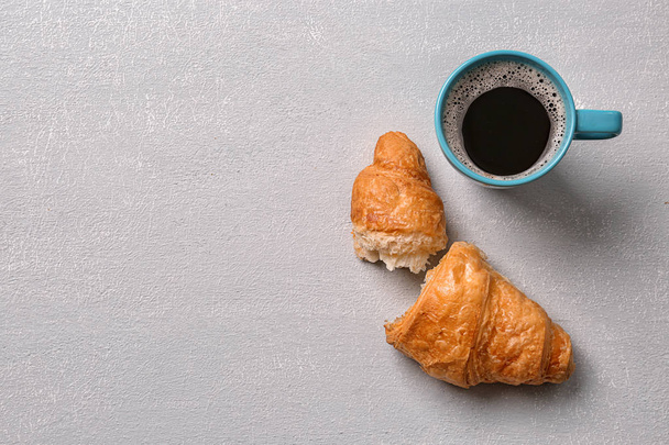 Tasty croissant and cup of coffee on light background, top view - Φωτογραφία, εικόνα