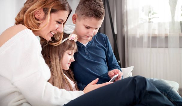 Young mother with children using digital tablet at home - Valokuva, kuva