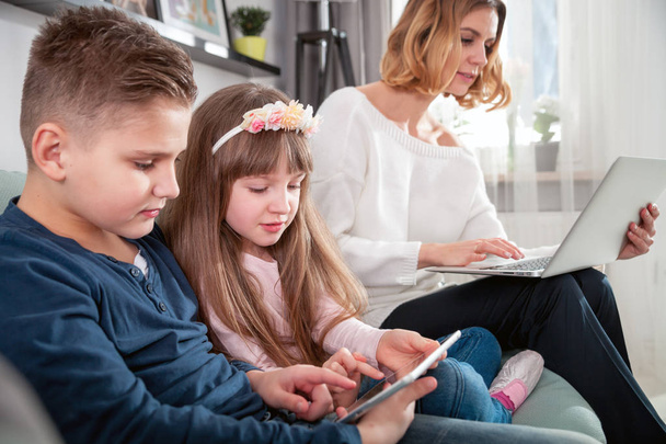 Young mother using laptop and children playing with tablet computer - Foto, Bild