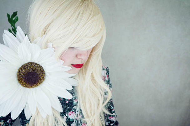 photo of young blonde woman with red lips in cute dress with big white daisy flower - Photo, Image