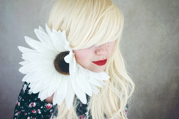 fiatal szőke nő, piros ajkak, nagy fehér Margaréta virág aranyos ruhában-fotó - Fotó, kép