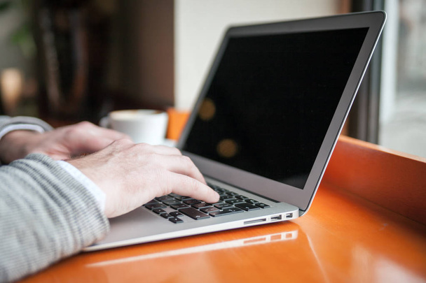 Close view of man typing on laptop keyboard in cafe - Fotó, kép