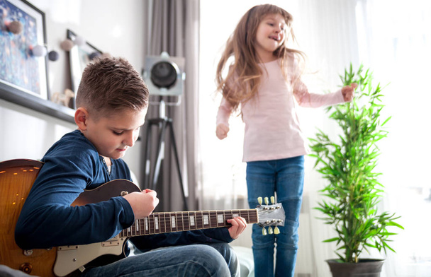 Preteen boy playing electric guitar with sister at home - Fotografie, Obrázek