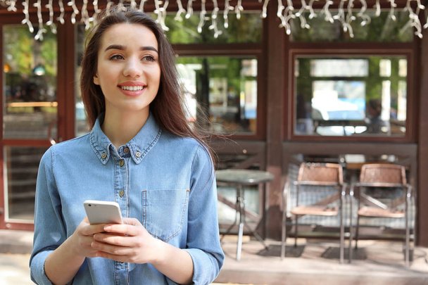 Young woman using mobile phone outdoors - Photo, Image