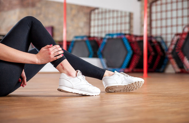Injured fit woman feeling pain in ankle at fitness gym - Fotografie, Obrázek