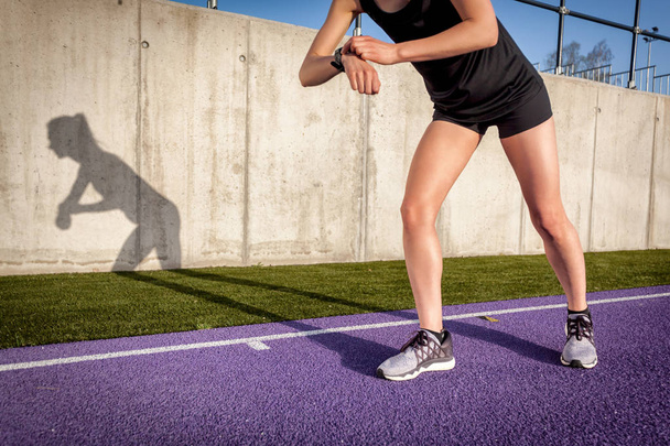 Woman running on stadium track and setting up fitness smart watch - Фото, зображення