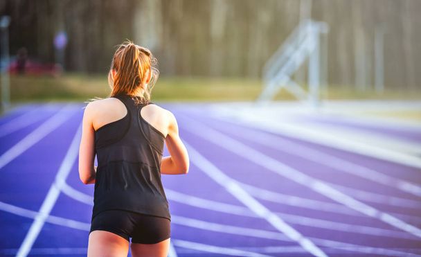 Back view of athletic woman starting training on running track - Fotoğraf, Görsel