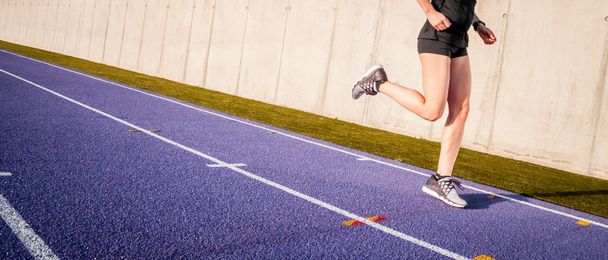 Legs of athlete woman running on racetrack on stadium track - 写真・画像