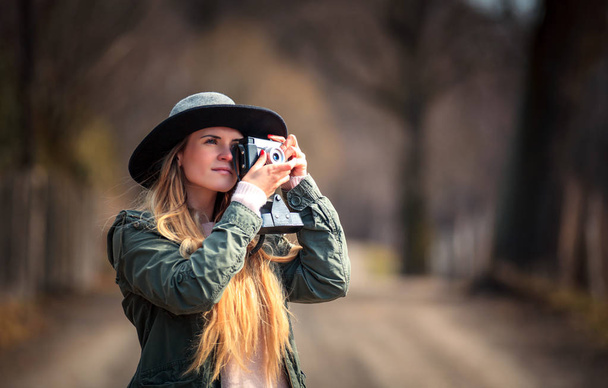 Young woman with vintage camera walking on rural area - Foto, Bild