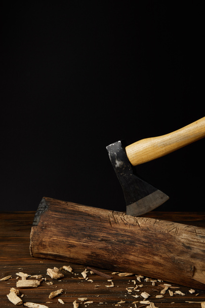 close up view of sticking axe in log and wooden chips on black background  - Фото, зображення