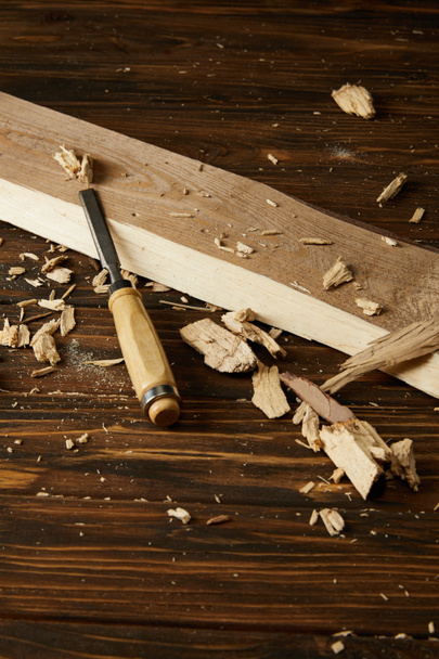 Nahaufnahme von Meißel und Holzstücken auf braunem Tisch  - Foto, Bild